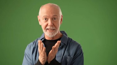 Sakallı olgun bir adam, neşeli hareketlerle gülümserken duygularını belli eder. Ayarlar, onun ifadesel duruşunu geliştiren katı yeşil ekran arkaplanı içeriyor..