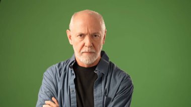 Olgun bir adam bir eliyle diş ağrısından yüzünü tutar ve derin düşüncelere dalmış bir duygu gösterir. Katı yeşil bir ekrana karşı duruyor, düşünceli tavrını vurguluyor..