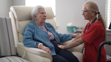 Bakıcı yaşlı bir kadına rahatlatıcı bir masaj teklif eder, stresi azaltmak ve rahat bir ortamda rahatlamayı teşvik etmek için baskı noktalarına odaklanır..