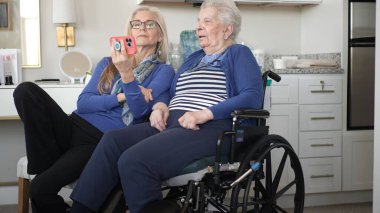 Bir kız ve yaşlı annesi evde sıcak bir video sohbetinin tadını çıkarıyorlar. Değerli anılarını yakalıyorlar ve sevgi ve destekle bağlarını güçlendiriyorlar..