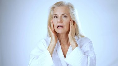 Beyaz cüppeli olgun bir kadın kaplıcada iken mutluluğunu ifade eder. Rahatlatıcı atmosferde güneşlenirken elleri nazikçe boynuna dokunur ve pozitif enerji saçar..