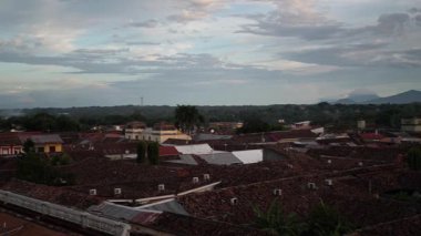 Gün batımında Granada, Nikaragua 'nın çarpıcı bir görüntüsü, ön planda terracotta çatıları ve titreşen gökyüzüne karşı büyük bir katedralin siluetini barındırıyor..