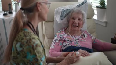 Hoş bir hemşire, huzur evinde gülümseyen yaşlı bir kadınla sohbet ederken hayati organlarını kontrol eder..