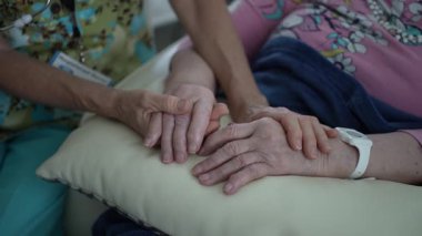 Bir hemşire yaşlı bir kadının elini nazikçe tutarak şefkatli bir sağlık hizmetleri ziyareti sırasında duygusal destek ve sıcaklık sağlar..