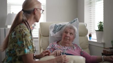 Mutlu, gülümseyen, kendini işine adamış bir hemşire yaşlı bir kadının oksijen seviyesini ölçmek için, rutin bir sağlık değerlendirmesi sırasında sağlığını sağlama almak için bir oksimetre kullanır..