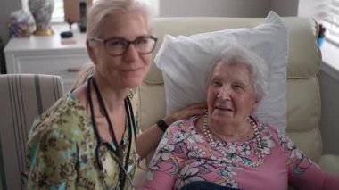 Hemşire, yaşlı bir kadının yaşam tesisine yaptığı dostça bir ziyaret sırasında hayati organlarını kontrol eder. Sıcak sohbete katılır ve ona destek olur..
