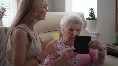 Olgun bir kadın yaşlı annesinin saçlarını nazikçe tarar. Aralarındaki yakınlık ve şefkat dolu bir anı teşvik eder..