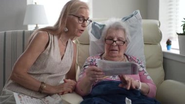 Rahat bir huzurevinde, bir kız ve yaşlı annesi bir fotoğraf albümünden hatıralarını paylaşırken birlikte gülümsüyor ve neşe anları yaratıyorlar..