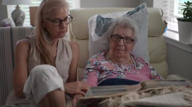 Huzurevinde, bir kız ve yaşlı annesi hatıralarla dolu bir fotoğraf albümünü anarken gülümsüyorlar..