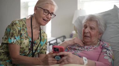 Huzurevine yapılan bir ziyarette, bir hemşire ve yaşlı bir kadın akıllı telefon kullanarak anılarını ve bilgilerini paylaştılar..