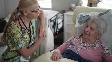 Gülümseyen hoş bir hemşire, yaşlı bir kadının huzur evine yaptığı ziyarette hayati organlarını kontrol eder..