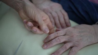 Hemşire, yaşlı bir kadının tırnaklarını kısaltmak için bir törpü tutuyor. Bakım ve konfora önem veriyor..