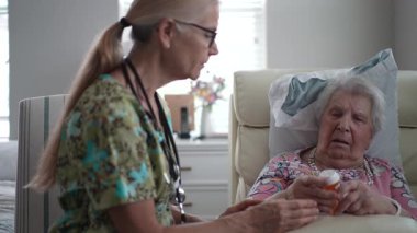 Keyifli bir hemşire yaşlılar yurdundaki yaşlı bir kadının reçetesini kontrol eder ve hastaların rahatlığını ve bakımını arttıran bir konuşma yapar..