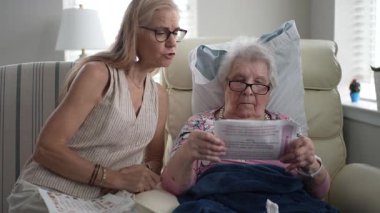 Yaşlılar için bir huzurevinde, olgun bir kız, yaşlı annesiyle neşeli bir anı paylaşıyor, hatıralarla dolu bir fotoğraf albümüne bakıyor..