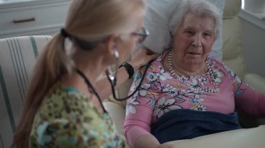 Hoş bir hemşire, yaşlı bir kadının, huzur evinde dostça sohbet ederken hayati organlarını kontrol eder..