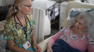 Son sınıf öğrencisi bir kadın, huzurevinde hayati organlarını kontrol eden bir hemşireyle neşeli bir konuşma yapıyor..