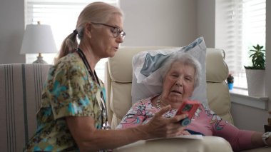 Hemşire ve yaşlı bir kadın, huzur evinde hayati organlarını kontrol ederken dostça bir konuşma yaparak bakım için destekleyici bir ortam yaratıyorlar..