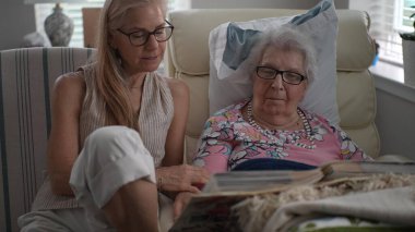 Huzurevinde, bir kız ve yaşlı annesi hatıralarla dolu bir fotoğraf albümünü anarken gülümsüyorlar..