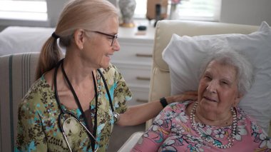 Gülümseyen hemşire, huzur ve bakım tesisinde yaşlı bir kadının hayati organlarını kontrol ederken dostça bir sohbete girişir..