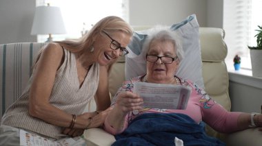 Rahat bir huzurevinde, bir kız ve yaşlı annesi bir fotoğraf albümünden hatıralarını paylaşırken birlikte gülümsüyor ve neşe anları yaratıyorlar..