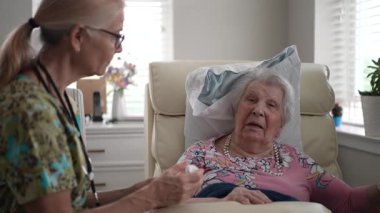 Hemşire, huzur veren bir yaşam tesisinde, sıcak bir bakım ve destek ortamı yaratarak, yaşlı bir kadının hayati organlarını kontrol ediyor..