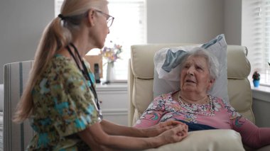 Hoş bir hemşire yaşlı bir kadınla yakınlaşır, gün boyunca huzur evinde dostça sohbet ederken elini tutar..