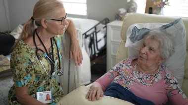 Gülümseyen hoş bir hemşire, yaşlı bir kadının huzur evine yaptığı ziyarette hayati organlarını kontrol eder..