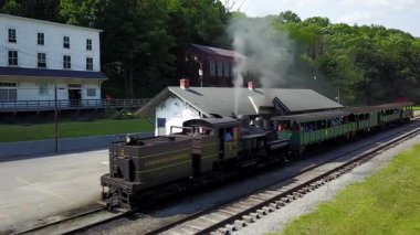 Trenin tepesinden gelen düdük beyaz buharla çaldığında siyah tren motorunun etrafında dönen hava kamerası..