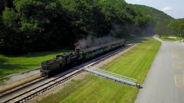 Cass Olay Yeri İnceleme trenini izleyen hava kamerası yolcularla dolu bir istasyona doğru giderken birkaç turist vagonunu geriye çekiyor..