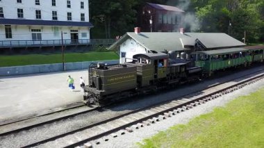 Kamera siyah motor boyunca hareket ederken turistler trenden iniyor..