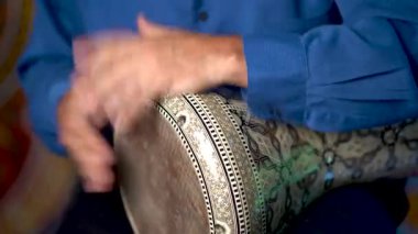 Dombek davulunun ritmini Arap arkaplanına göre yavaş çalan ellerin yakın çekimi.