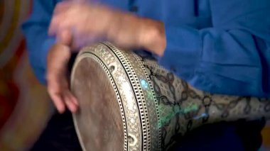 Doumbek davulunun ritmini arap arkaplanlı yavaş ritmiyle çalan ellerin yakın çekimi.