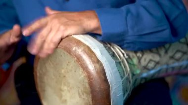 Kil tamponda balık derisi kafayla hızlı ritim çalan ellerin yakın çekimi.