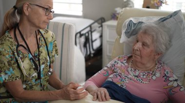 Dost canlısı bir hemşire yaşlı bir kadının hayati organlarını dikkatle kontrol eder. Huzur ve bakım sağlamak için huzurevinde sohbet ederler..