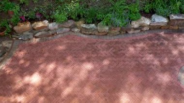 Hava manzarası, bahçeli kaya duvarına bakıyor. Bahçeler, arka bahçedeki verandada, ringa kemiği tuğlası deseniyle ormana karışıyor..