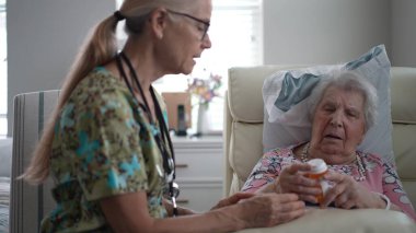 Keyifli bir hemşire yaşlılar yurdundaki yaşlı bir kadının reçetesini kontrol eder ve hastaların rahatlığını ve bakımını arttıran bir konuşma yapar..