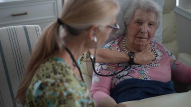 Hoş bir hemşire, yaşlı bir kadının, huzur evinde dostça sohbet ederken hayati organlarını kontrol eder..