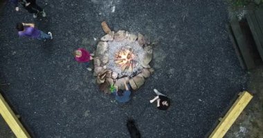 Ateş çemberindeki bir yangının üzerine inen hava kamerası ateşin etrafında lokum kızartan bir aileyi gösteriyor..