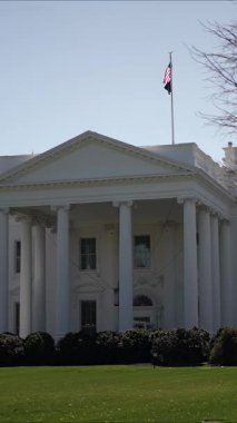 Beyaz Saray 'ın dikey videosu Washington DC' de bir bahar günü açık mavi bir gökyüzünün altında iyi korunan çimlerle ve ağaçlarla çevrili..