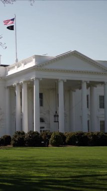 Dikey video. Ziyaretçiler, Washington DC 'de çiçek açan ağaçlar ve yemyeşil çimlerle çevrili Beyaz Saray' da mevsimin güzelliğini yansıtan bir bahar gününün keyfini çıkarıyorlar..