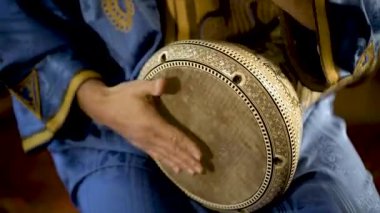 Fas elbiseli bir adamın Arap doumbek, darbuka ya da derbeki oynarken çekilmiş resmi.