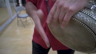 Ahşap zemin döşenmiş odada aynalı bir kayışla inci kabuklu kukla oynayan adamın sağlam bir görüntüsü..