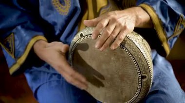 Fas elbiseli bir adamın Arap doumbek, darbuka ya da derbeki oynarken çekilmiş resmi.