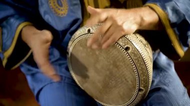 Fas elbiseli bir adamın Arap doumbek, darbuka ya da derbeki oynarken çekilmiş resmi.