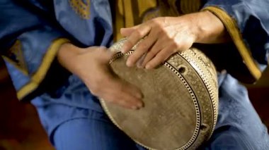 Fas elbiseli bir adamın Arap doumbek, darbuka ya da derbeki oynarken çekilmiş resmi.