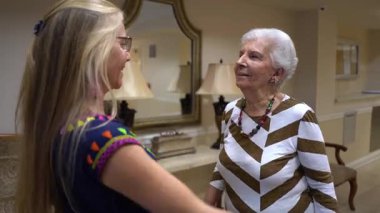 Yaşlı bir kadın, lobide etnik bluzlu genç bir kadına sarılıyor..