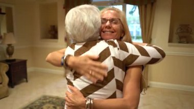 Kamera, yaşlı kadınlara sarılıp sırt sıvazlayan sarışın bir kadının yörüngesinde dönüyor..