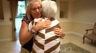 Kamera, yaşlı kadınlara sarılıp sırt sıvazlayan sarışın bir kadının yörüngesinde dönüyor..