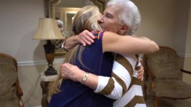 Sarışın kadın girerken gülümseyen yaşlı kadının yakın çekimi ve sarılmaları..