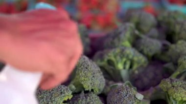 Biri pazarda onlara su sıkarken ön planda brokoli ile sağa kayın..